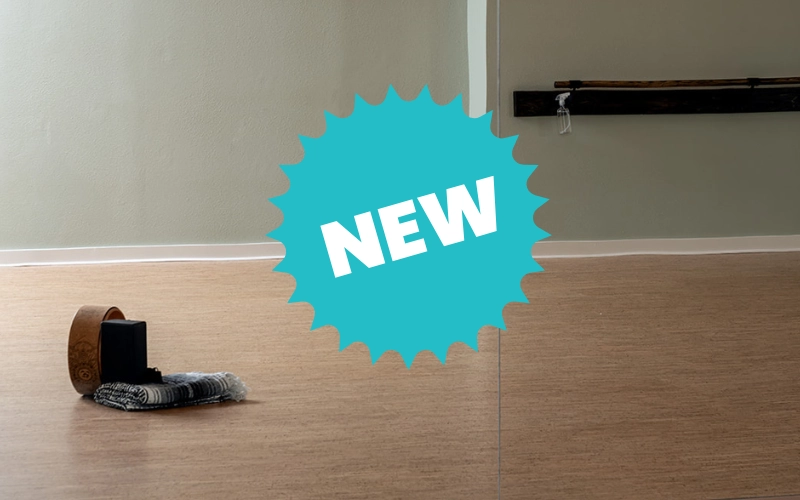 Glow Hot Yoga studio floor with a yoga block, strap, and towel beside a barre rail, with a "NEW" badge overlay announcing the Define class.