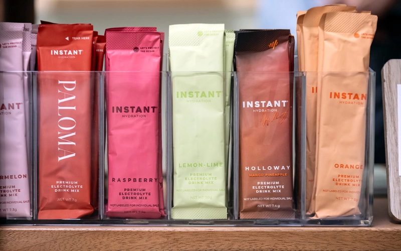 Instant Hydration electrolyte drink mix packets on display at Glow Hot Yoga Sarasota including Raspberry, Lemon-Lime, and Mango Pineapple flavors